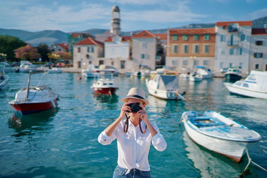 Joven haciendo fotos en la costa Dálmata tras alquilar un barco en Croacia title=